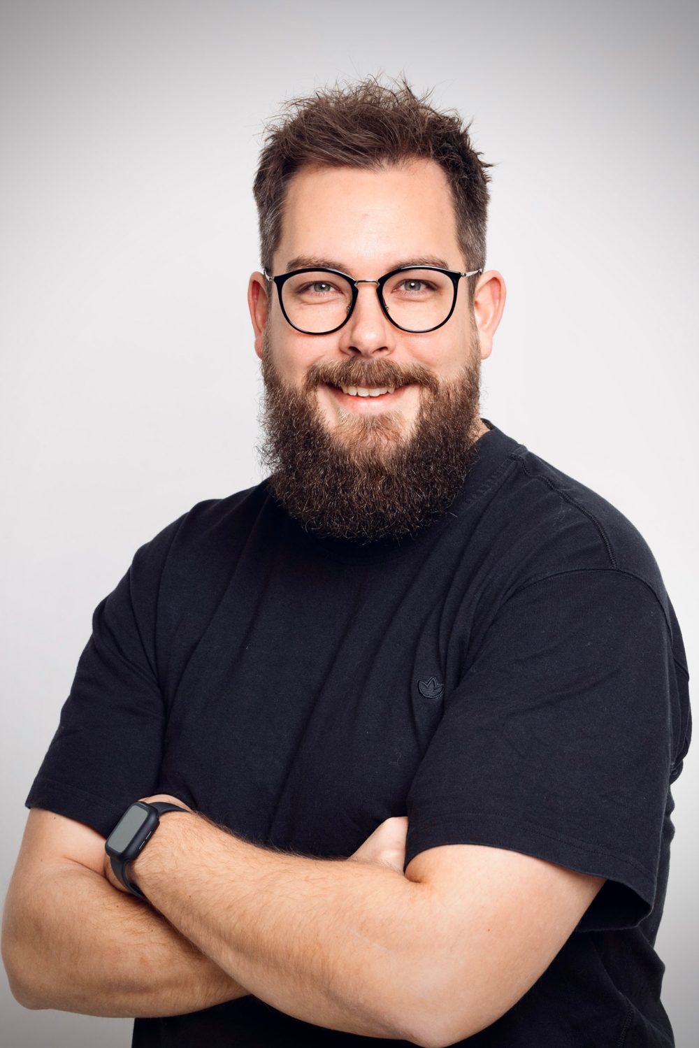 Lars, App-Marketing-Experte, lächelnd mit verschränkten Armen
